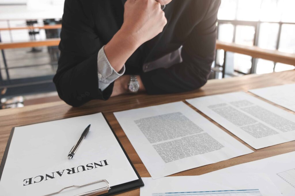 Insurance agent reviewing policy documents and claim paperwork at office desk.