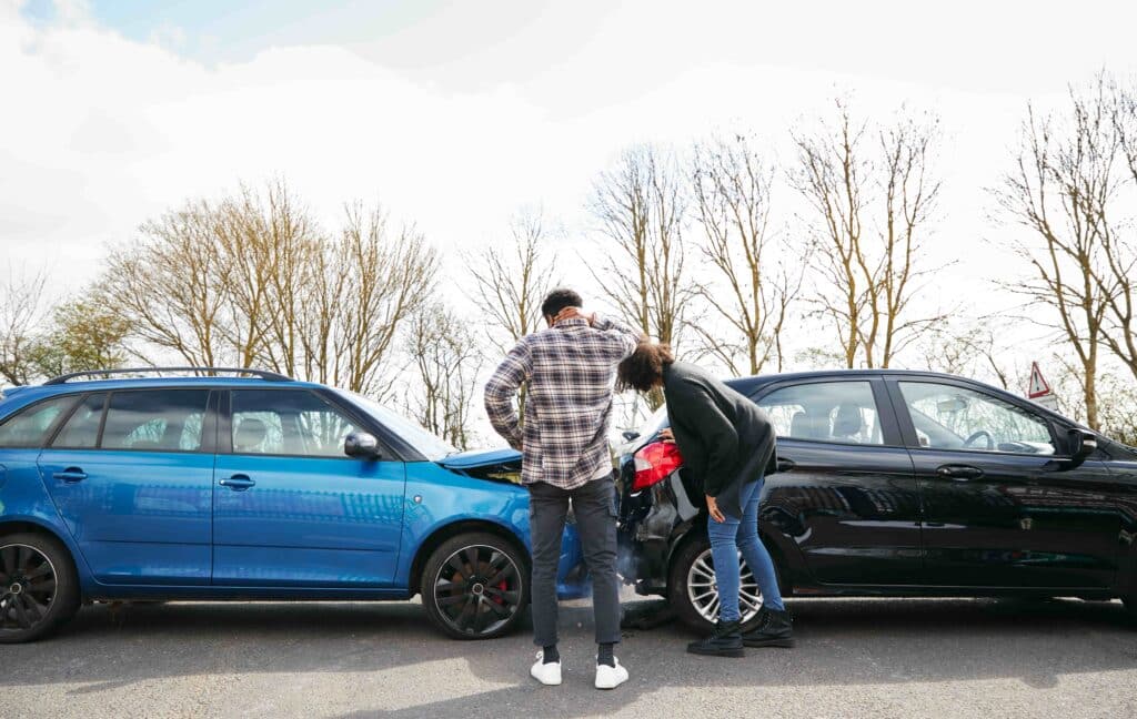 Drivers inspecting vehicle damage after a rear-end car accident on the road.