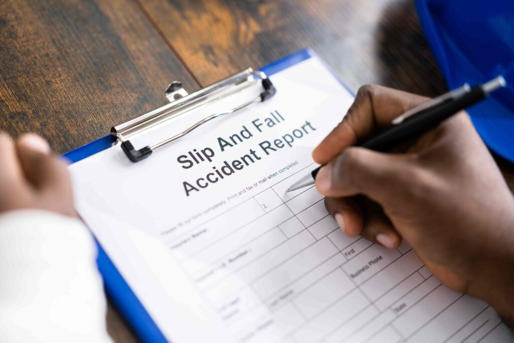 Person filling out slip and fall accident report form after workplace or store injury. Person filling out slip and fall accident report form after workplace or store injury.